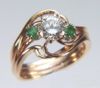 Item# CD4: 14kt yellow hand made engagement ring set with a 1.34ct round brilliant cut diamond and two 4mm emeralds.