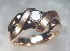 Custom 14kt yellow gold diamond band with swirl pattern. The piece is set with a .80ct center diamond and ten .06ct side diamonds.