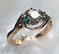 14Kt yellow gold 'Oriel' Engagement Ring set with  a 1.0ct round brilliant cut diamond and two .10ct round emeralds.